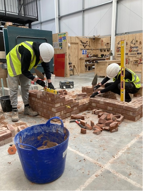 Apprentices building a brick wall